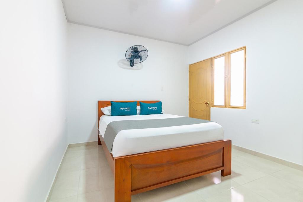 a bedroom with a bed with blue pillows on it at Hotel Tu Casa Bambú in Valledupar