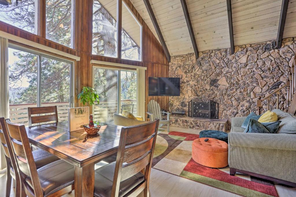 a living room with a table and a stone wall at Quaint Cabin Retreat about 4 Mi to Arrowhead Lake in Lake Arrowhead