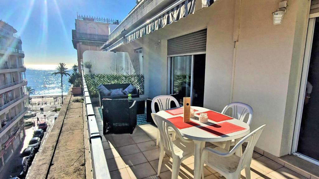 a balcony with a table and chairs and a view of the ocean at Le Meyerbeer Promenade in Nice