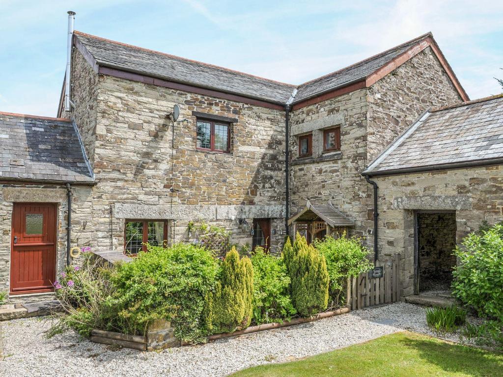 an old stone house with a red door at Nightingale Cottage in Liskeard