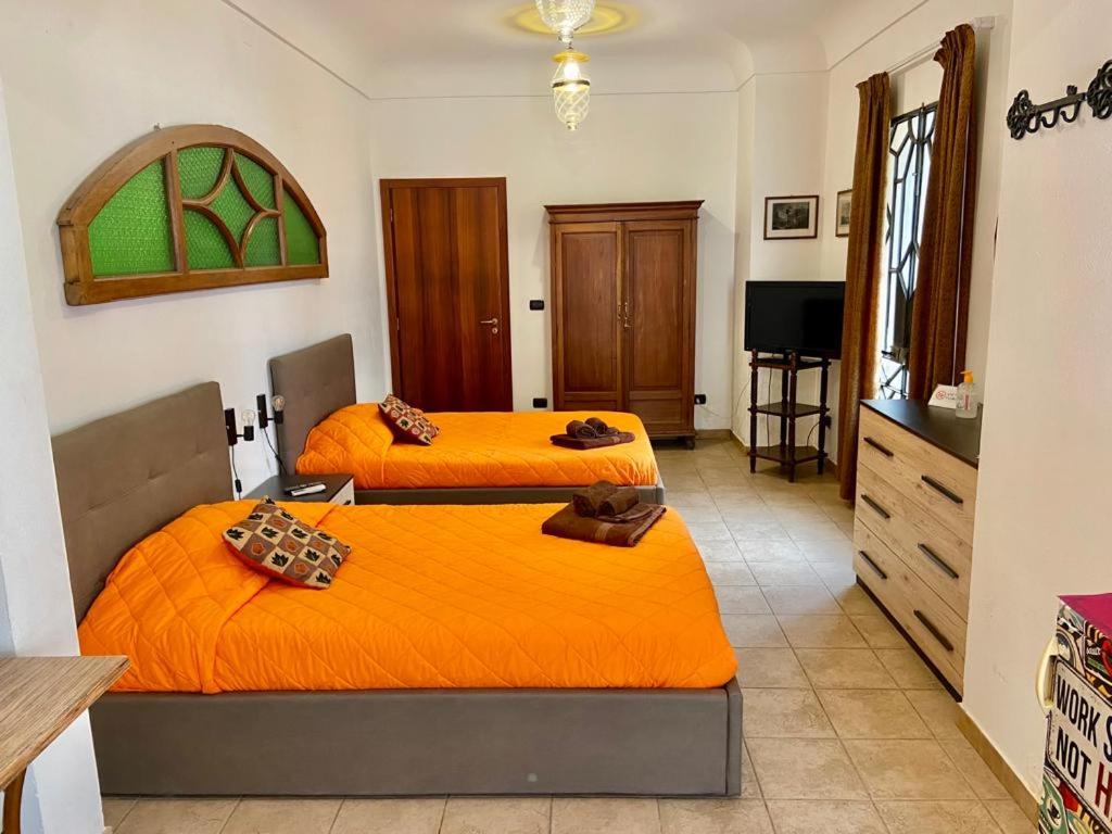 ガラティーナにあるCasa di Marcoのオレンジのシーツが備わる客室内のベッド2台