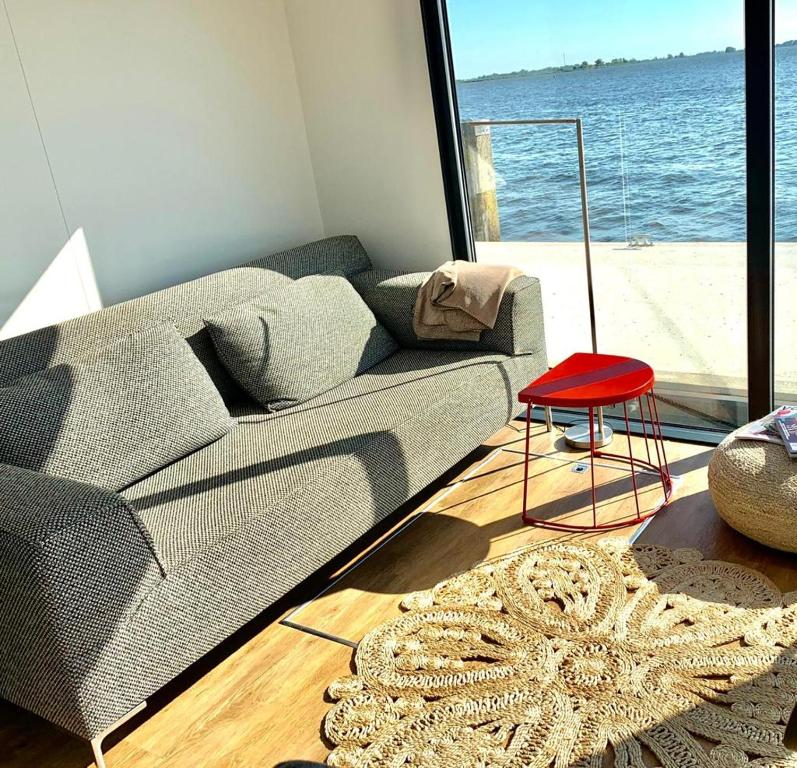 sala de estar con sofá y taburete rojo en Houseboat Earebarre - Waterrijck Sneekermeer, Sneek - Offingawier, en Offingawier