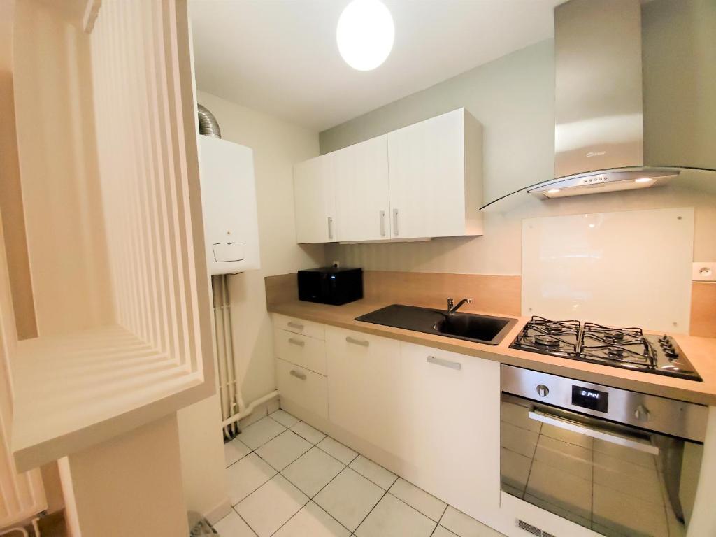 a kitchen with white cabinets and a stove top oven at Standing appartement avec vue sur la Mayenne in Laval