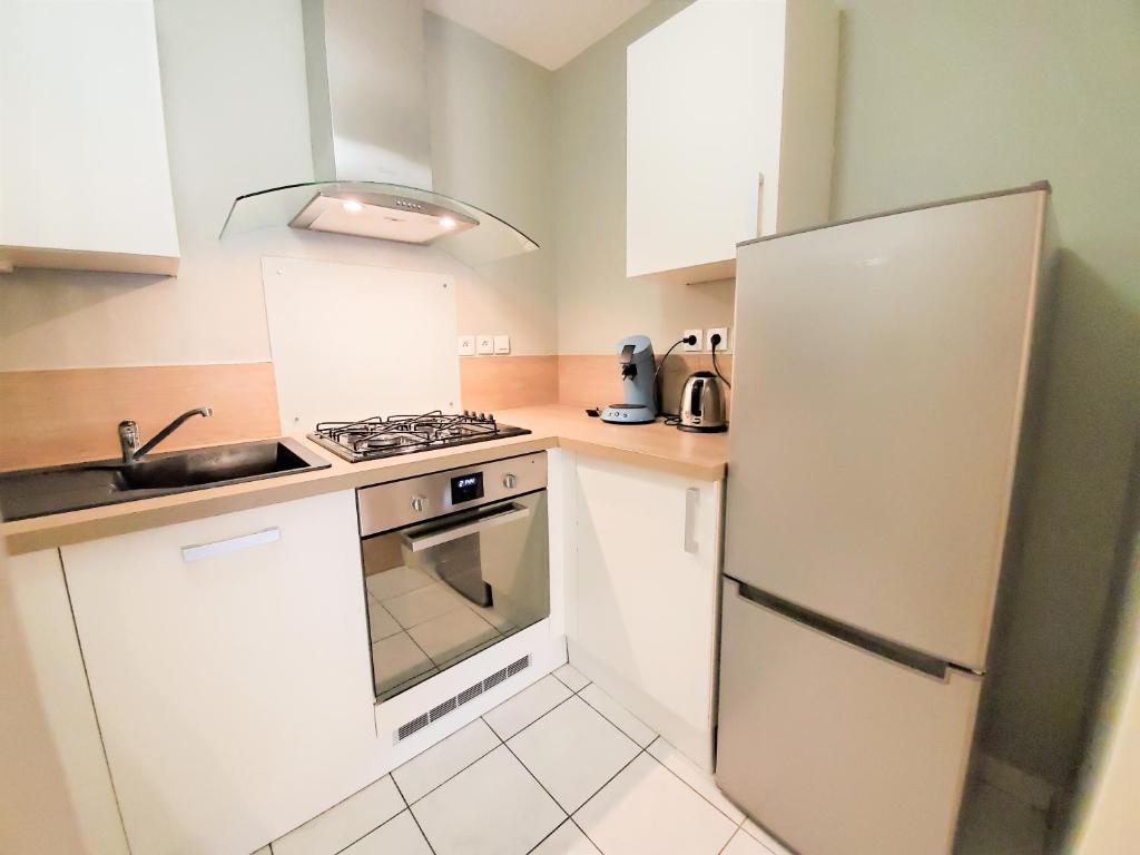 a small kitchen with a stove and a refrigerator at Standing appartement avec vue sur la Mayenne in Laval