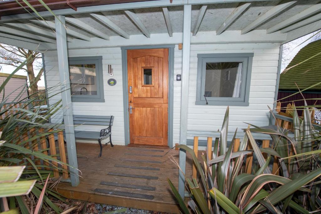 een huis met een houten deur en een bank op een veranda bij Seaways glamping, Cedar in Great Driffield