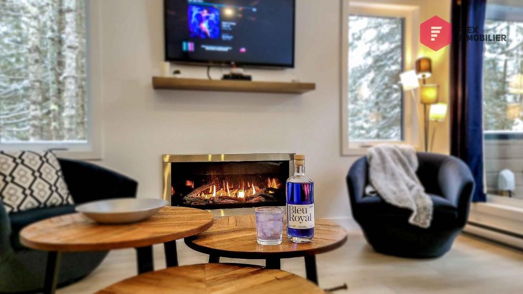 - une bouteille de booze assise sur une table devant une cheminée dans l'établissement Le Bleu Bourgeois de Portneuf - Natural Elegance - Hot tub, sauna and pool, à Pont-Rouge