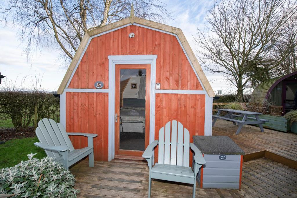 um pequeno barracão vermelho com duas cadeiras e uma mesa em Seaways glamping, Redwood em Great Driffield