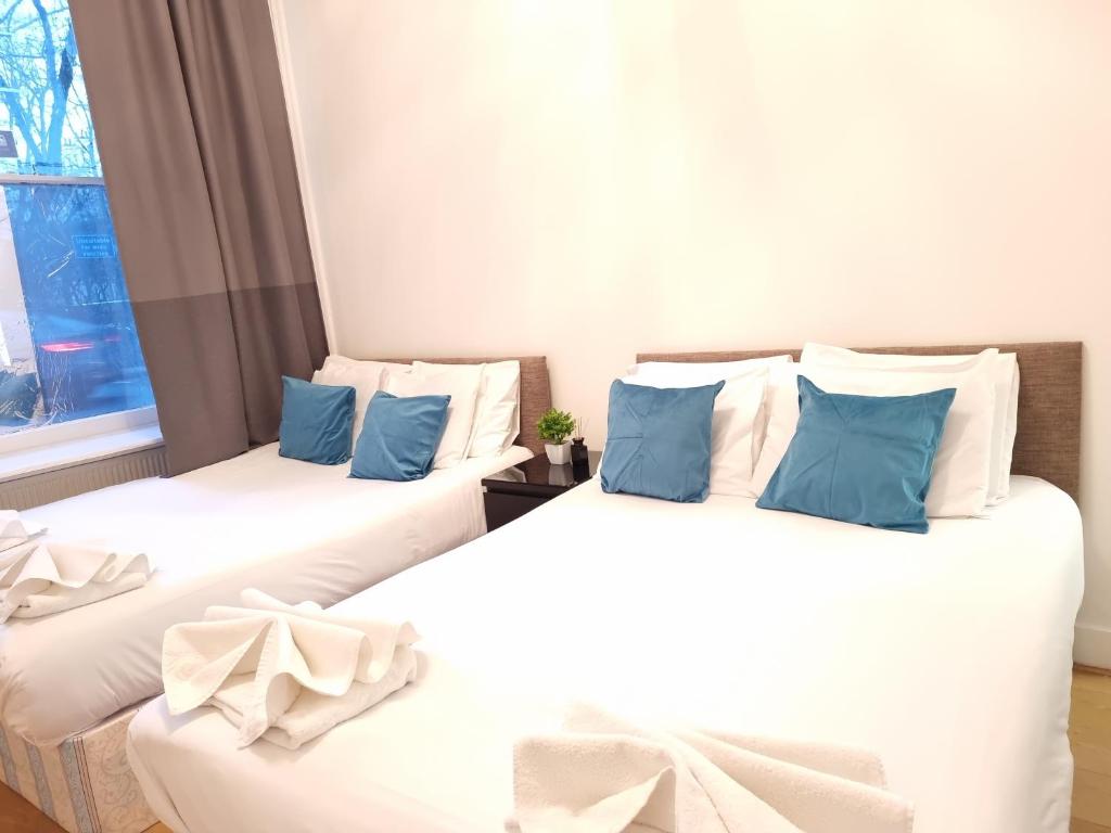 2 camas en una habitación con almohadas blancas y azules en F6-Comfy Ground Flr Studio Fits 4- Near Paddington, en Londres