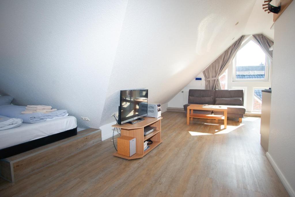 een woonkamer met een tv en een bed en een bank bij Ostut in Norderney