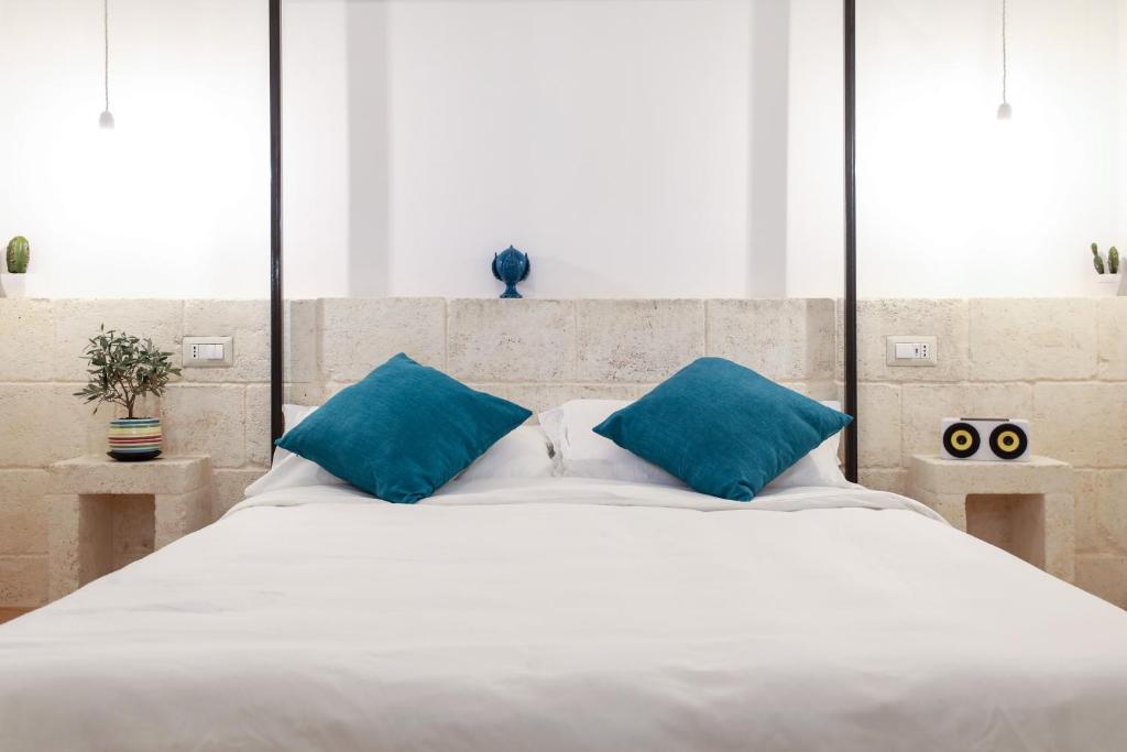 uma grande cama branca com almofadas azuis em D'Angiò Rooms-Manfredi Homes&Villas em Manfredónia