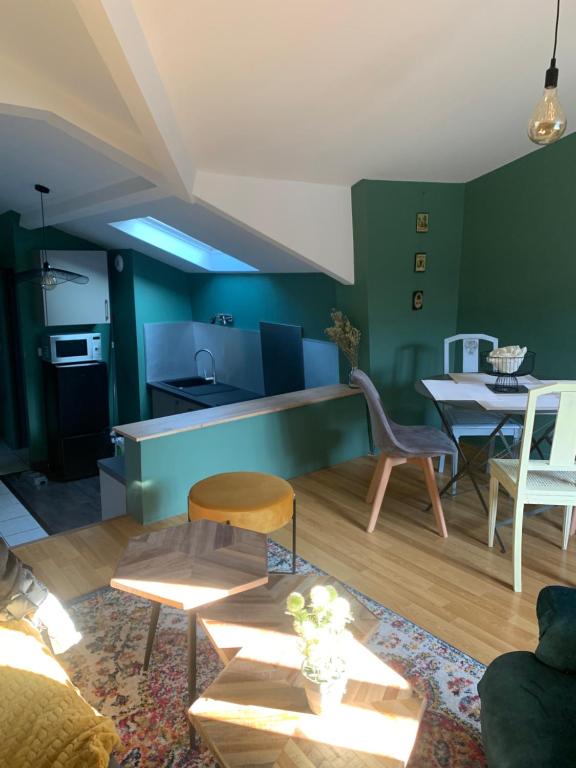 un soggiorno con pareti verdi, tavolo e sedie di Magnifique Appartement Neuf Vieux Rouen a Rouen