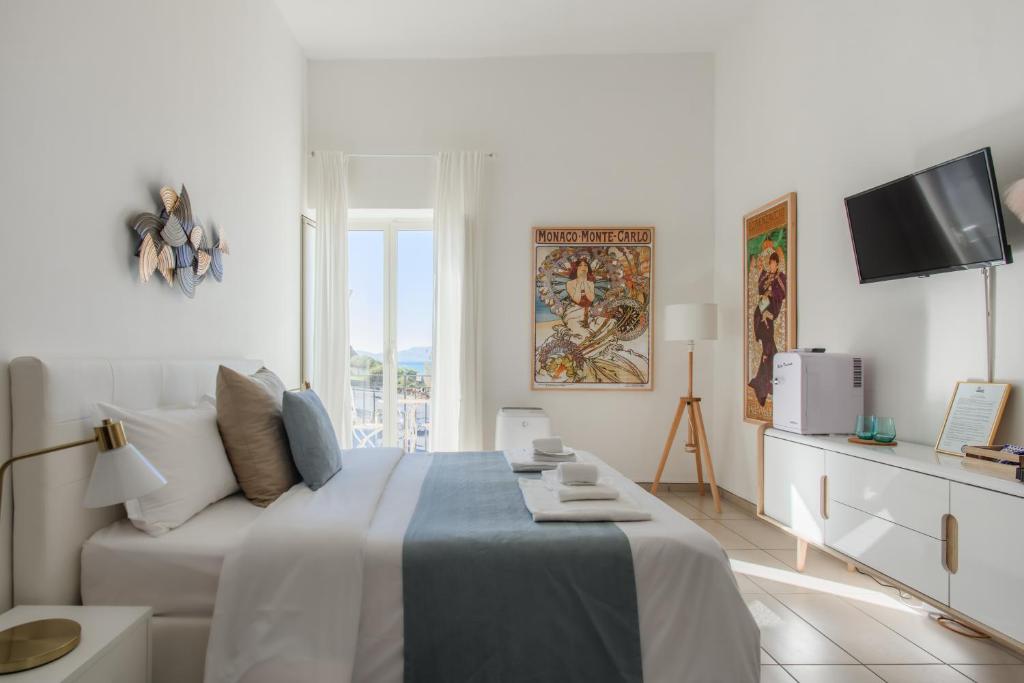 a white bedroom with a bed and a tv at Naro Suites and Rooms in Bacoli