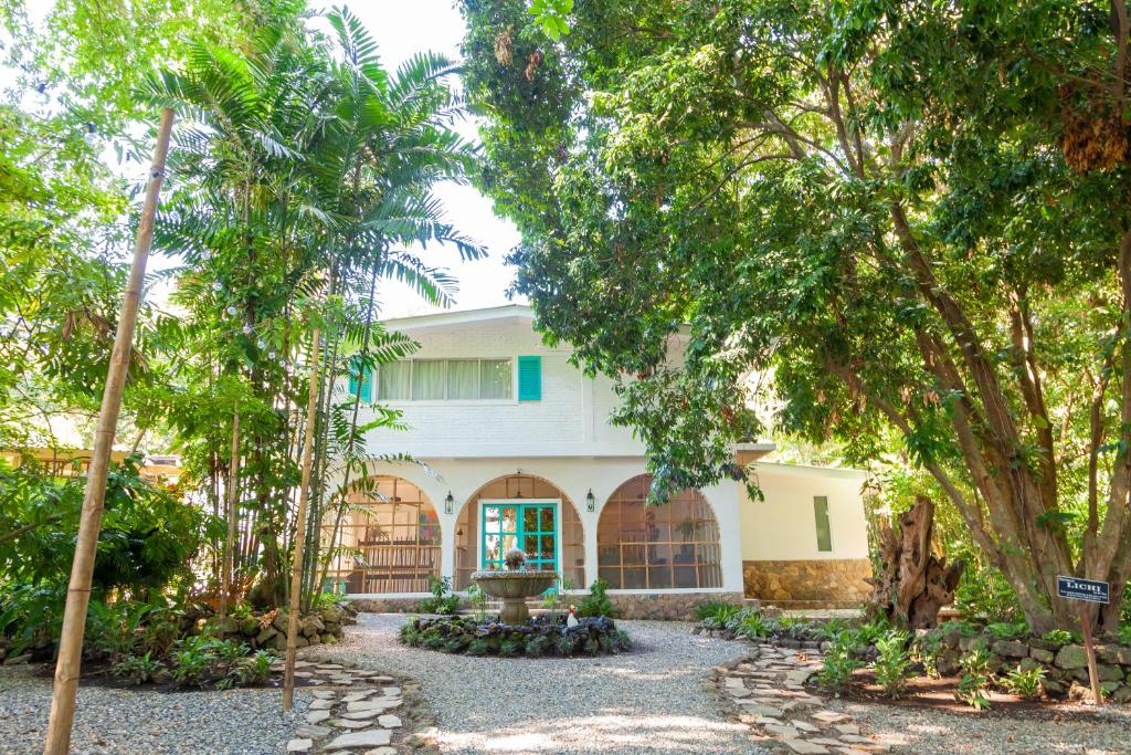 una casa blanca con árboles delante en Angeli Gardens Boutique Hotel, en San Pedro Sula
