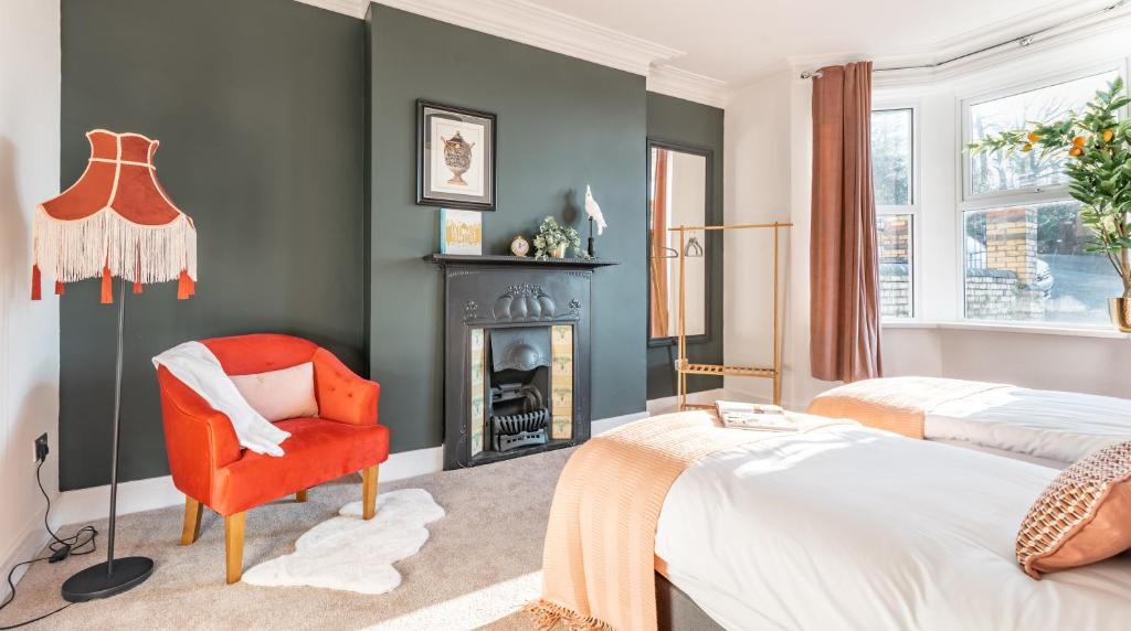 a bedroom with a red chair and a fireplace at Tŷ Hapus Newport - Luxury 4 Bedroom Home in Newport