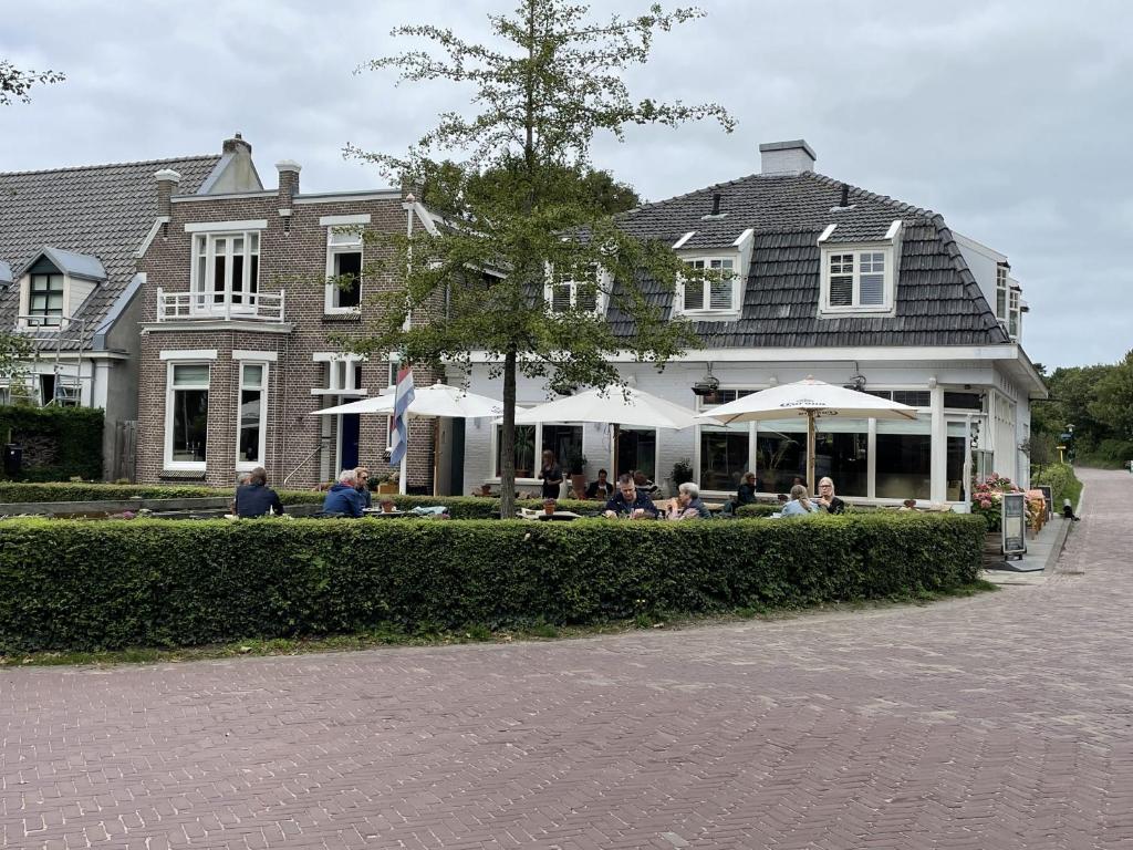 un grupo de personas sentadas frente a una casa en Hotel Brasserie Brakzand, en Schiermonnikoog