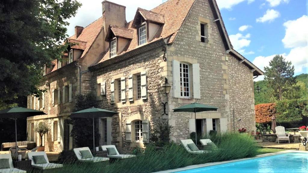 a building with a pool in front of a house at Manoir du Bois Mignon in Le Fleix