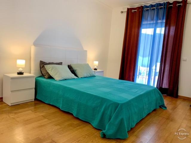 a bedroom with a bed with blue sheets and windows at Apartamento saloio in Venda do Pinheiro