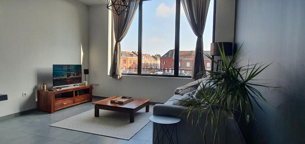 a living room with a couch and a table and windows at Appartement-chic parking privé in Tourcoing