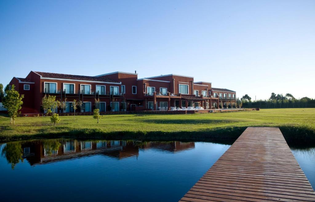 un edificio junto a un río con un puente en Pampas de Areco Resort de Campo & Spa en San Antonio de Areco