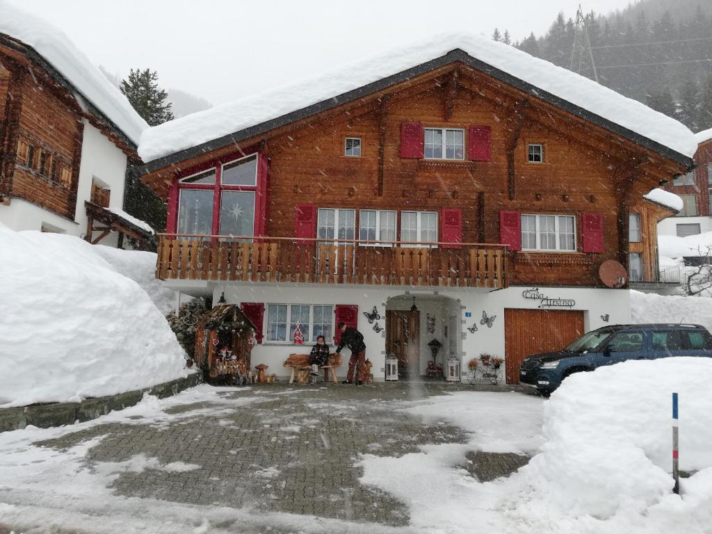 ein großes Holzhaus mit Balkon im Schnee in der Unterkunft Ferienwohnung Casa Ursina in Sedrun