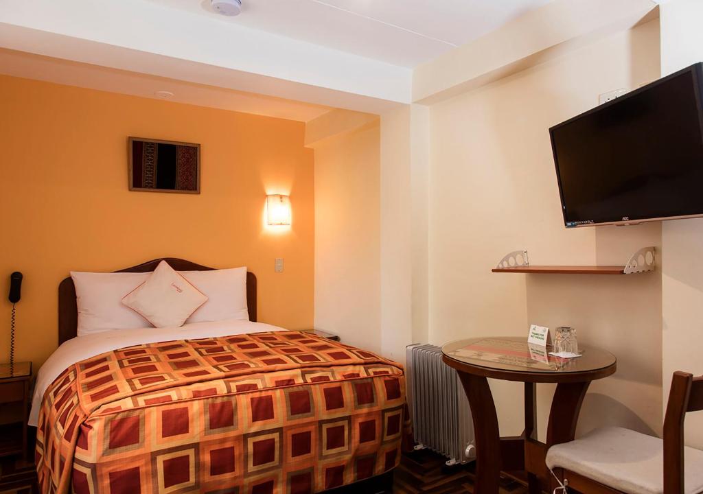 a hotel room with a bed and a table and a tv at Laramani Hotel Boutique in Cusco