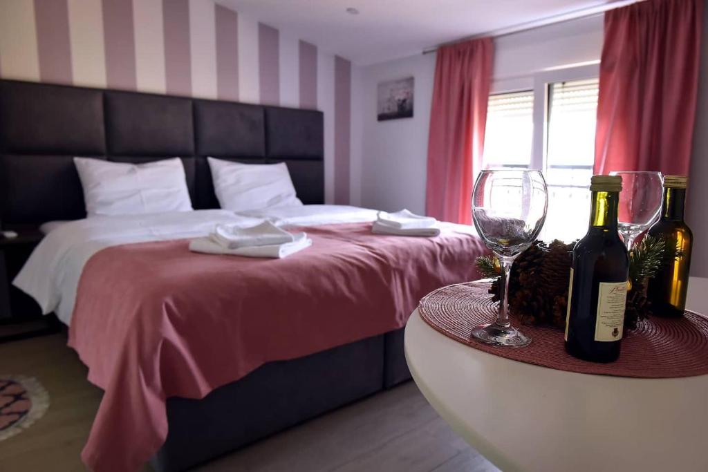 a bedroom with a bed and two bottles and glasses at Studio Apartments Bulevar in Podgorica