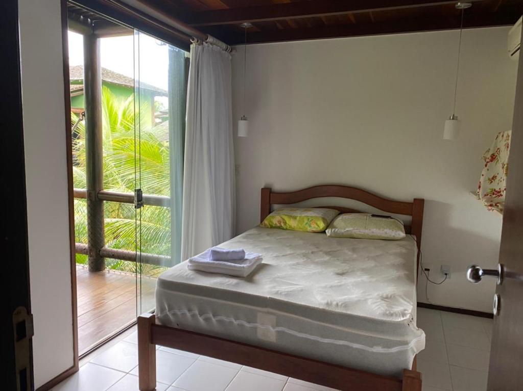 a bedroom with a bed and a large window at BANGALÔ - Varandas do Mar - Praia de Itacimirim in Camaçari
