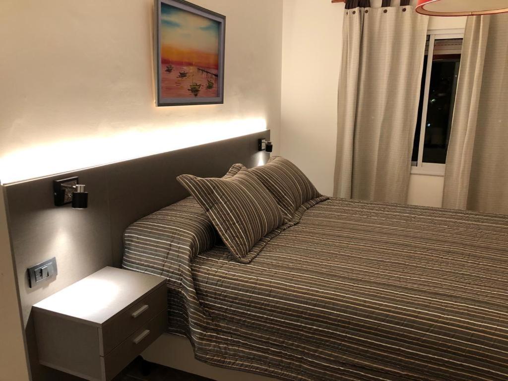 ein Schlafzimmer mit einem Bett und einem Nachttisch daneben in der Unterkunft Departamento Alberdi Completo con Cochera in Cordoba