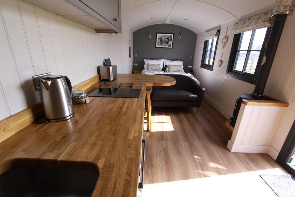 a kitchen and living room with a table in a trailer at Springwood Shepherd Huts Glamping York in York