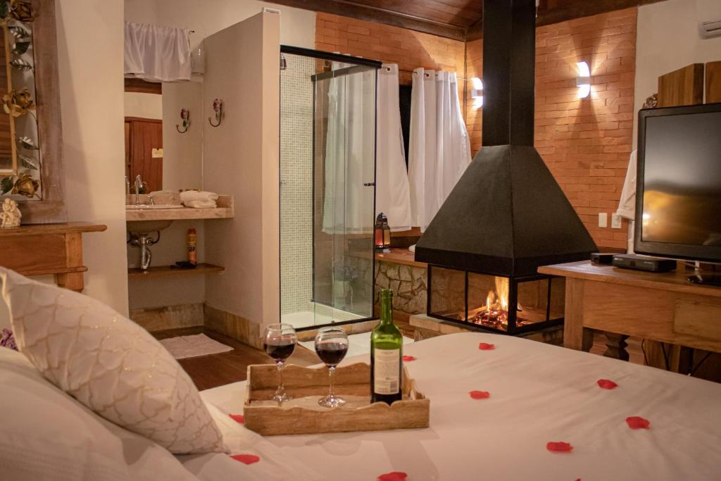 um quarto com uma cama com dois copos de vinho em Pousada Infinito em Visconde de Mauá