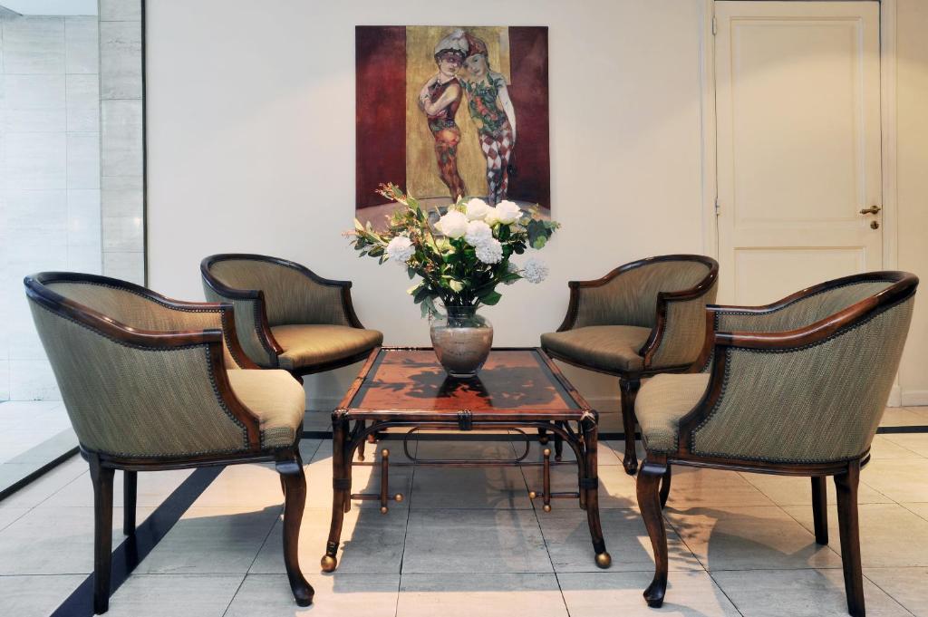 two chairs and a table with a vase of flowers at Mayla Apartments in Buenos Aires