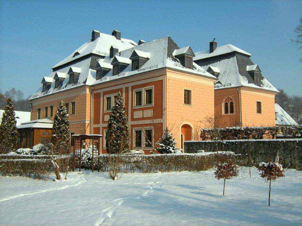 una casa grande de color naranja con techo cubierto de nieve en Pałac Książęcy we Wleniu, en Wleń