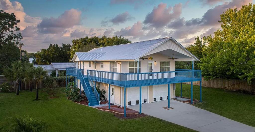 uma grande casa com um deque azul e um parque infantil em Five Bedroom Home in the Heart of St Aug Beach em Saint Augustine