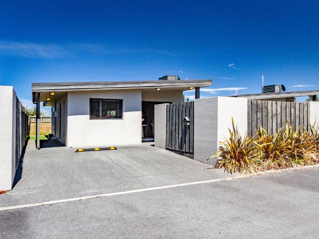 a white house with a gate and a driveway at Alpine Place - Spa and Mountain Views in Ohakune