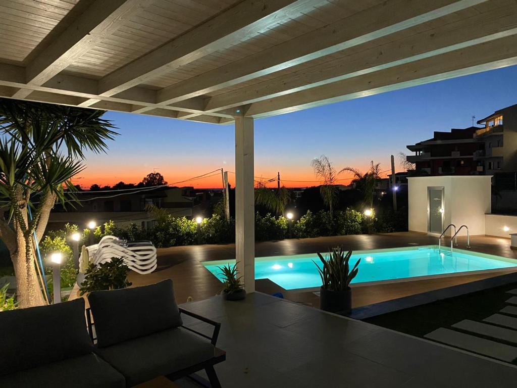 un patio trasero con piscina por la noche en Valenti rooms & relax, en Villaggio Mosè