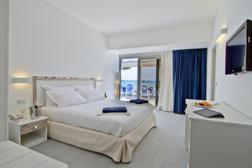 a bedroom with a large bed with a view of the ocean at Hotel Miramare in Marina di Ragusa