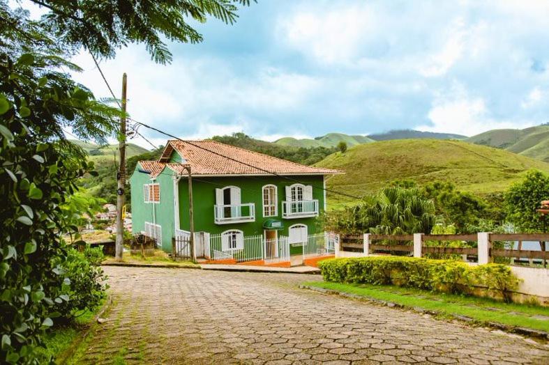 a green and white house with a cobblestone street at Pousada Conservatória in Conservatória