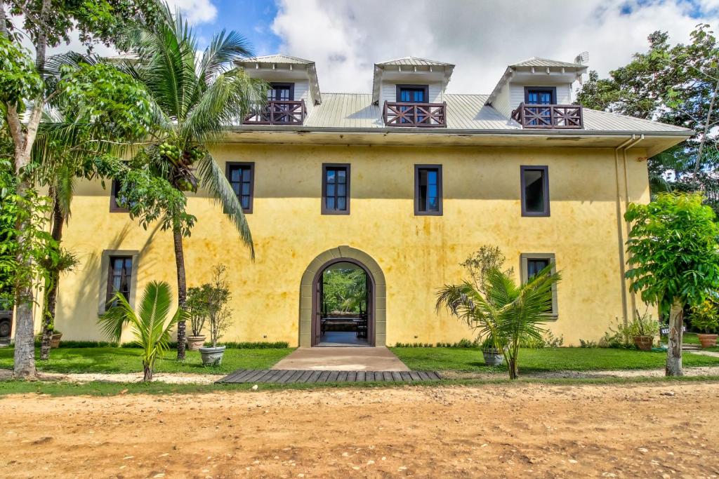 una vecchia casa gialla con palme di fronte di Mahogany Hall Gold Standard Certified a San Ignacio