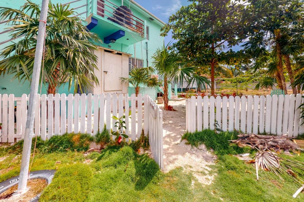 a white picket fence in front of a house at Almond Tree 3 at Island Cabanas Gold Standard Certified in Caye Caulker