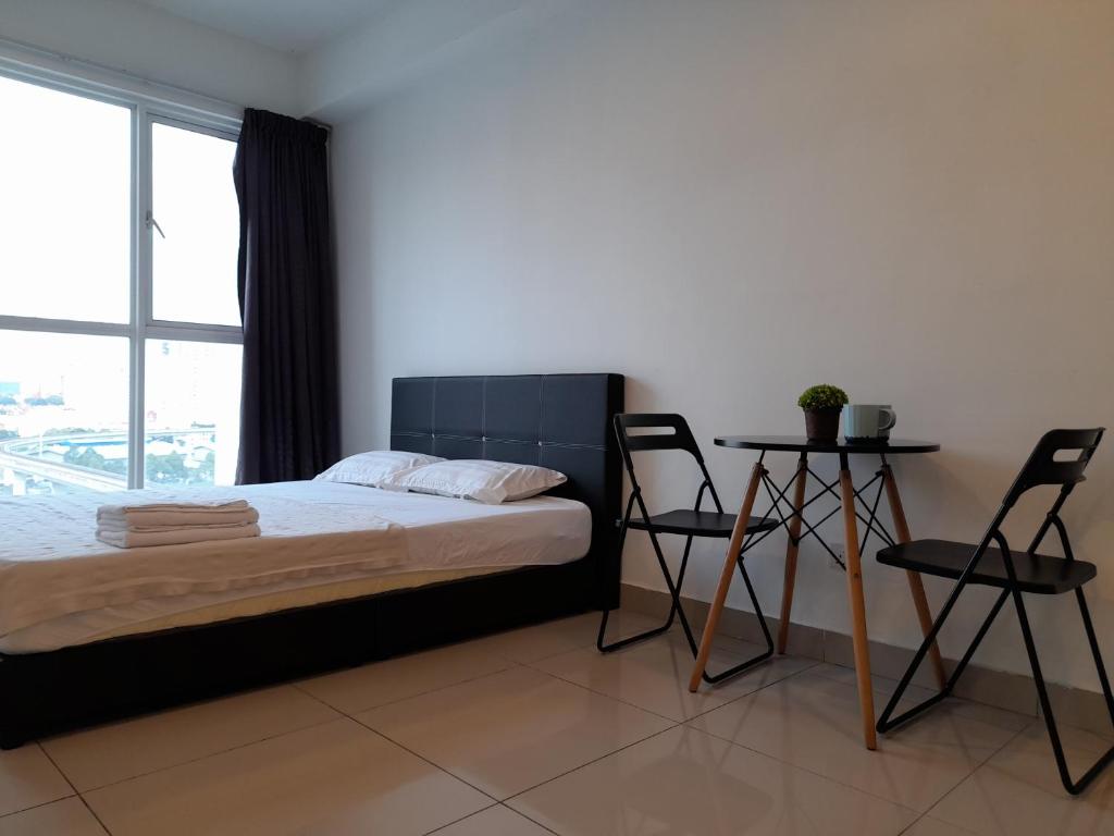 a bedroom with a bed and two chairs and a window at Pacific Place Evolve Mall LRT Pool Parking Netflix Kitchen in Petaling Jaya
