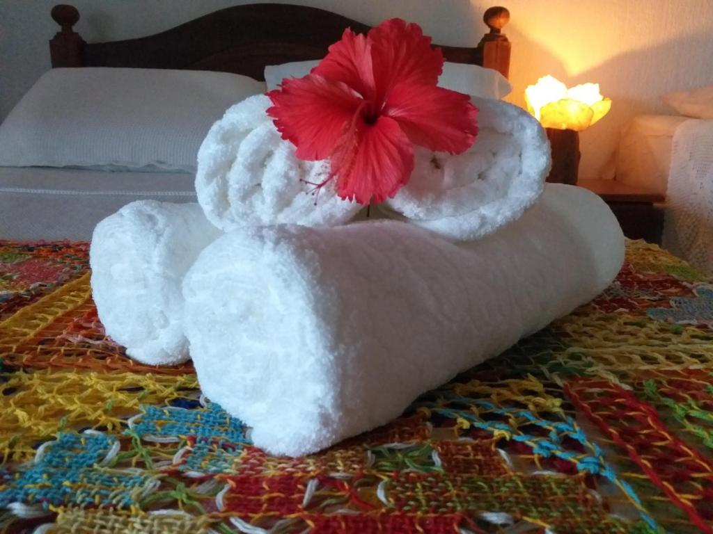 a towel animal with a red flower on top of a bed at Bangalô completo, amplo, funcional e confortável. in Fernando de Noronha
