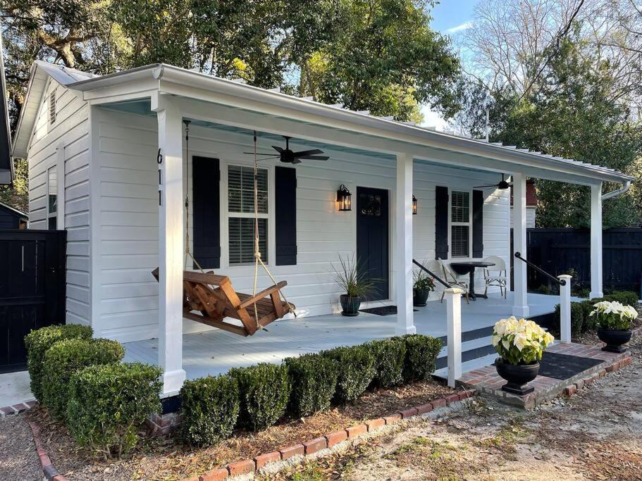 a white house with a porch with a swing at Cottage in Summerville