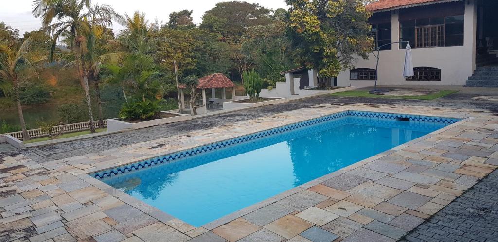 a swimming pool in front of a house at Chácara Beira Rio in Guararema