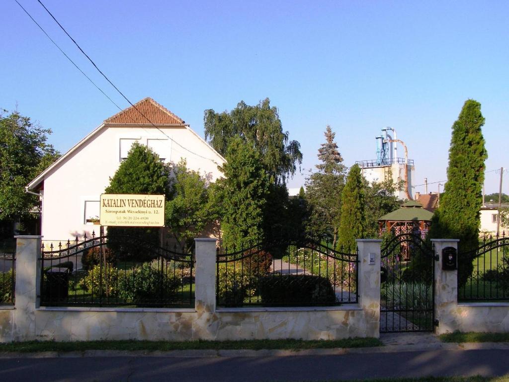 una recinzione di fronte a una casa bianca con un cartello di Katalin vendégház a Sárospatak