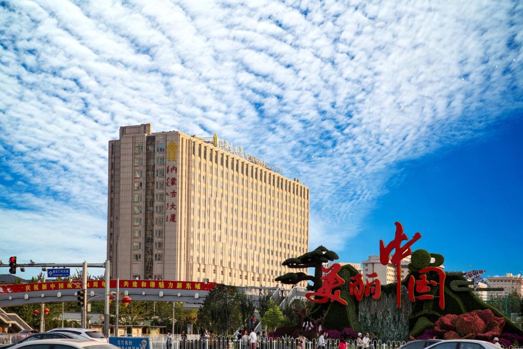 un grand bâtiment avec des nuages dans le ciel dans l'établissement Inner Mongolia Grand Hotel, à Pékin