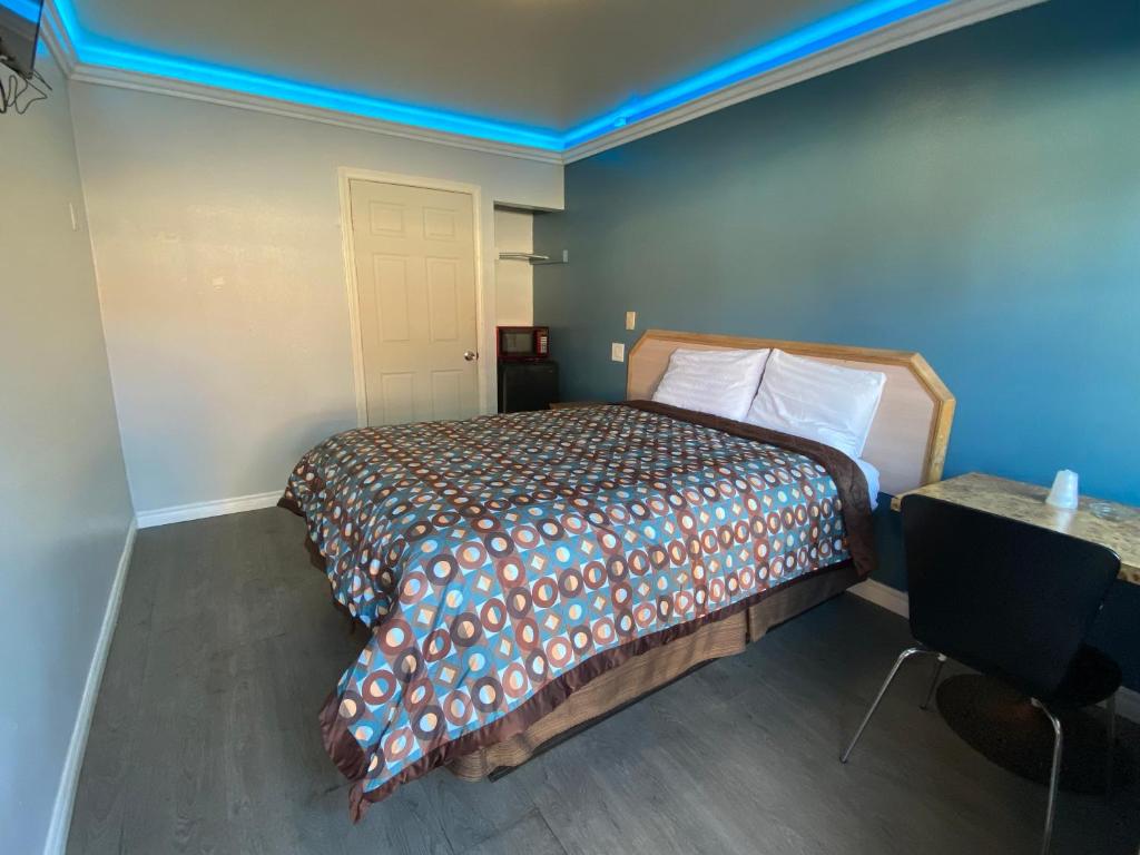a bedroom with a bed and a blue wall at Sands Inn in South Gate