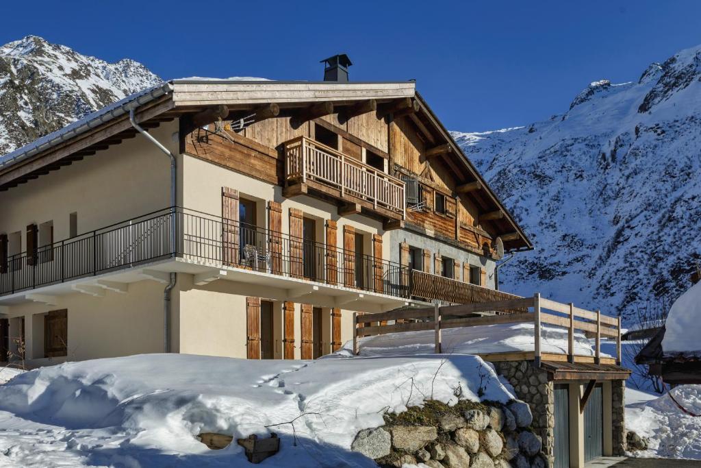 un grand bâtiment en bois dans la neige avec des montagnes dans l'établissement La Ferme à Roland ski in - ski out - Happy Rentals, à Chamonix-Mont-Blanc