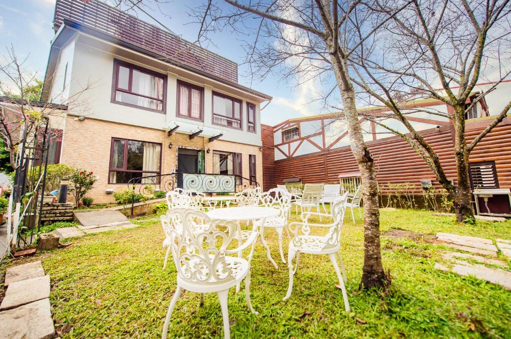 a group of white tables and chairs in front of a house at Moonlake B&amp;B in Yuchi