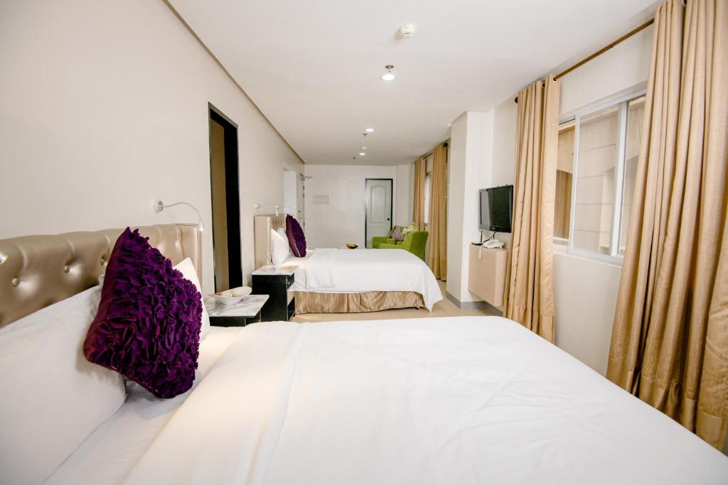 a hotel room with two beds and a tv at Sta Barbara Residence Hotel in Cebu City