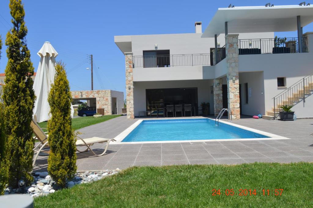 a villa with a swimming pool in front of a house at Villa Angela in Droushia